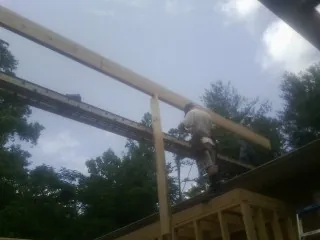 Carpenter setting a ridge beam over a new addition frame in Arcadia